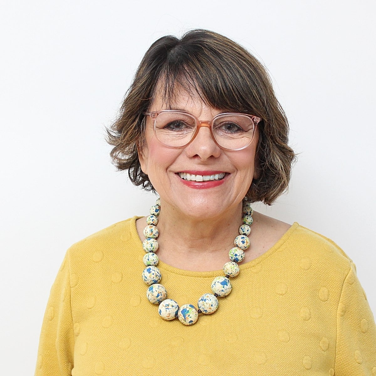 woman in yellow top wearing wood colorful necklace