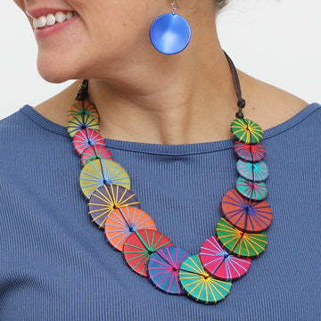 Colorful necklace with circular patterns worn by a person against a white background