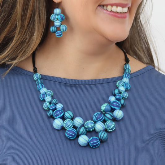 Woman wearing a blue beaded necklace and earrings against a neutral background