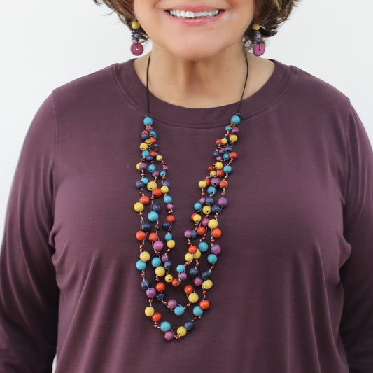 Woman wearing a colorful beaded necklace on a plain background