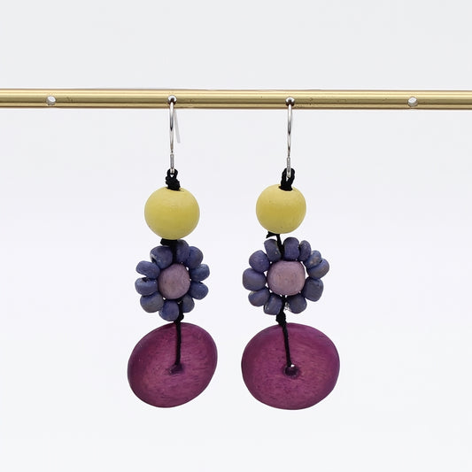 Pair of earrings with yellow beads and purple floral designs on a white background
