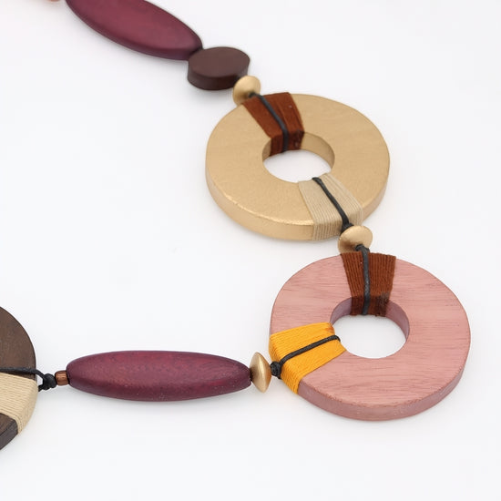 Colorful wooden necklace with circular and oval beads on a white background