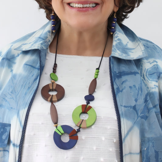 Woman wearing a colorful necklace with a blue jacket and white shirt.