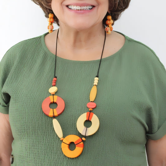 Woman wearing a colorful necklace with circular beads on a plain background