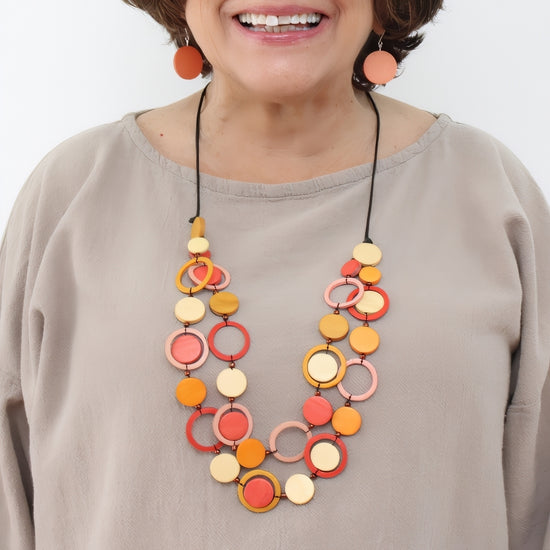 Woman wearing a colorful necklace with a plain background