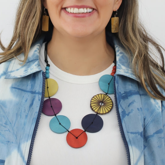 Woman wearing a colorful necklace with circular pendants on a white background