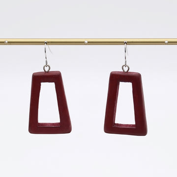 Pair of maroon square earrings on a gold rod against a white background