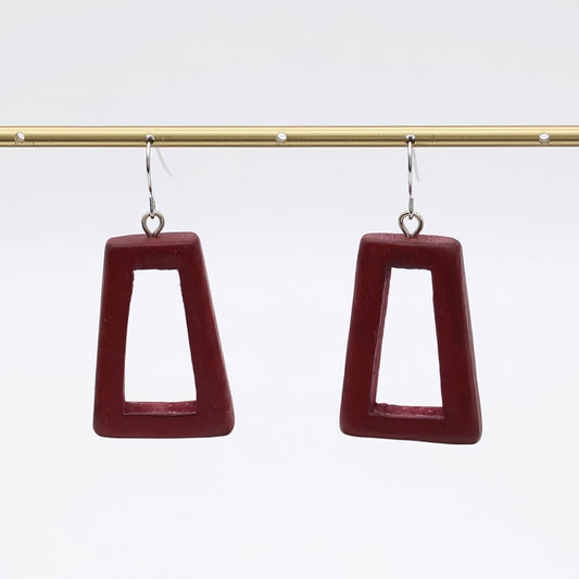 Pair of maroon square earrings on a gold rod against a white background