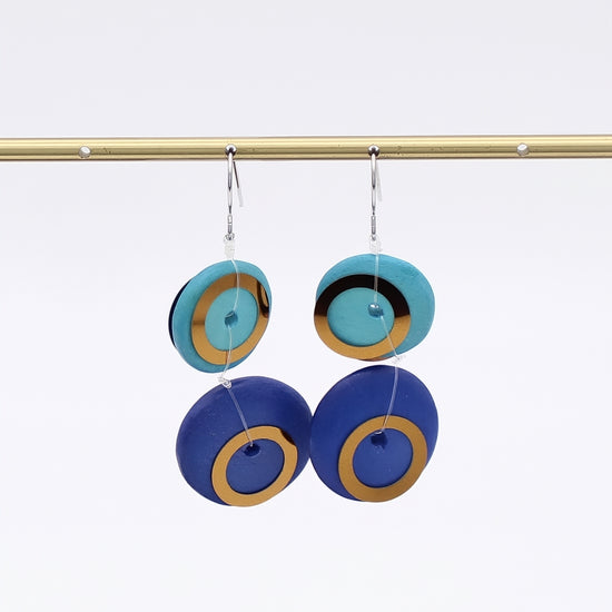 Pair of earrings with blue and gold circular design on a white background
