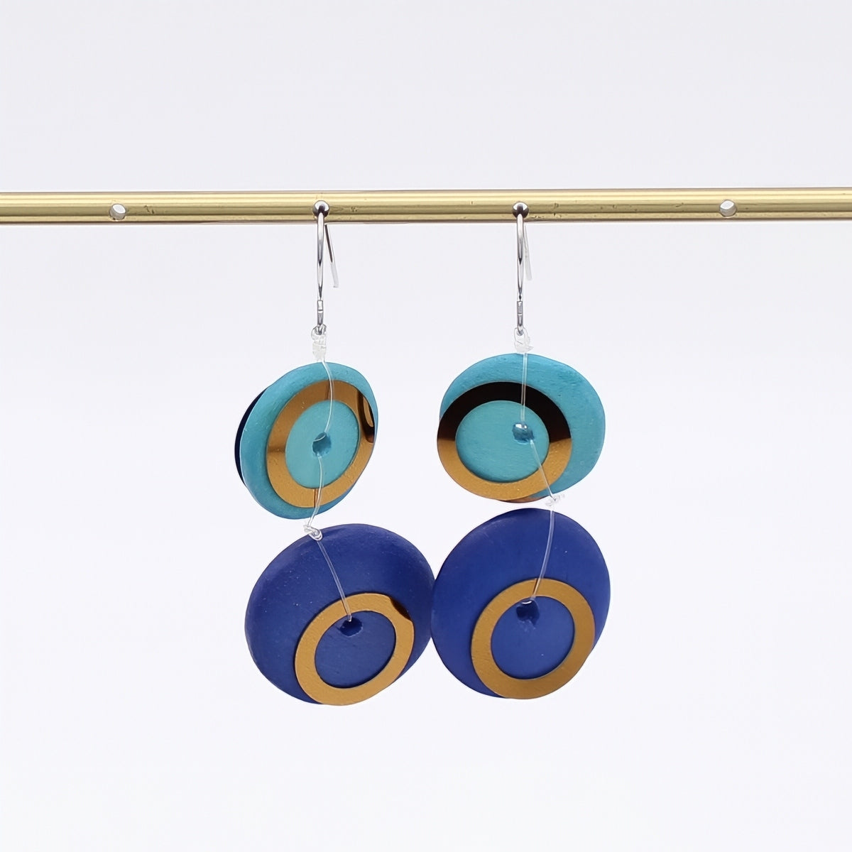 Pair of earrings with blue and gold circular design on a white background