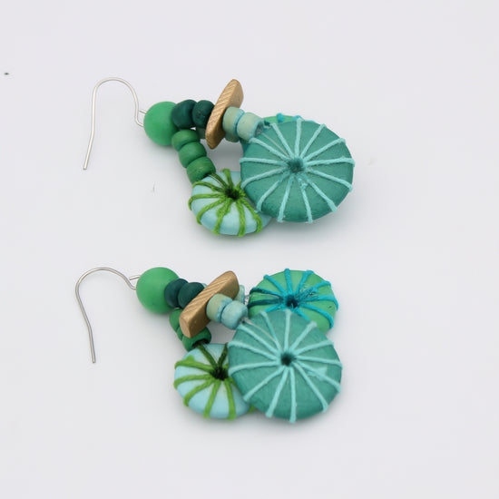 Green and blue beaded earrings on a white background