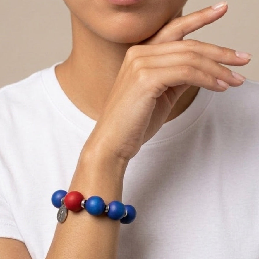 Person wearing a colorful beaded bracelet on a plain background