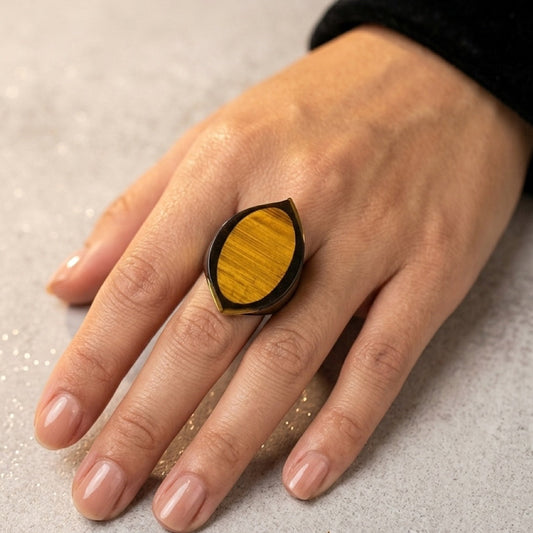 Hand wearing a ring with wood inlay on a neutral background