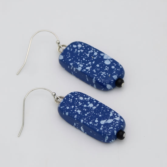 Blue speckled earrings on a white background