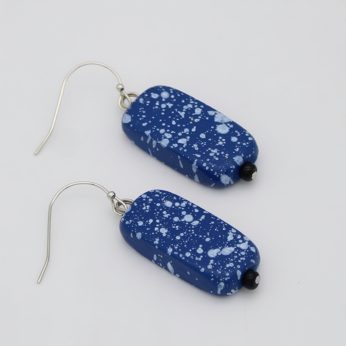 Blue speckled earrings on a white background