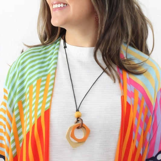 Woman wearing a colorful scarf and necklace with a white background