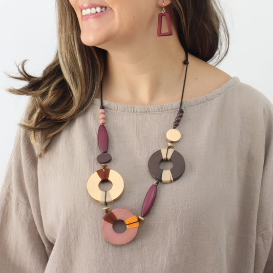 Woman wearing a colorful necklace and earrings on a plain background
