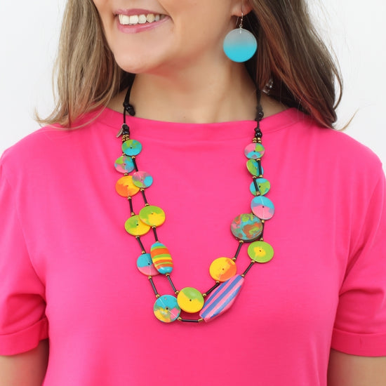 Person wearing a colorful necklace and pink shirt on a white background