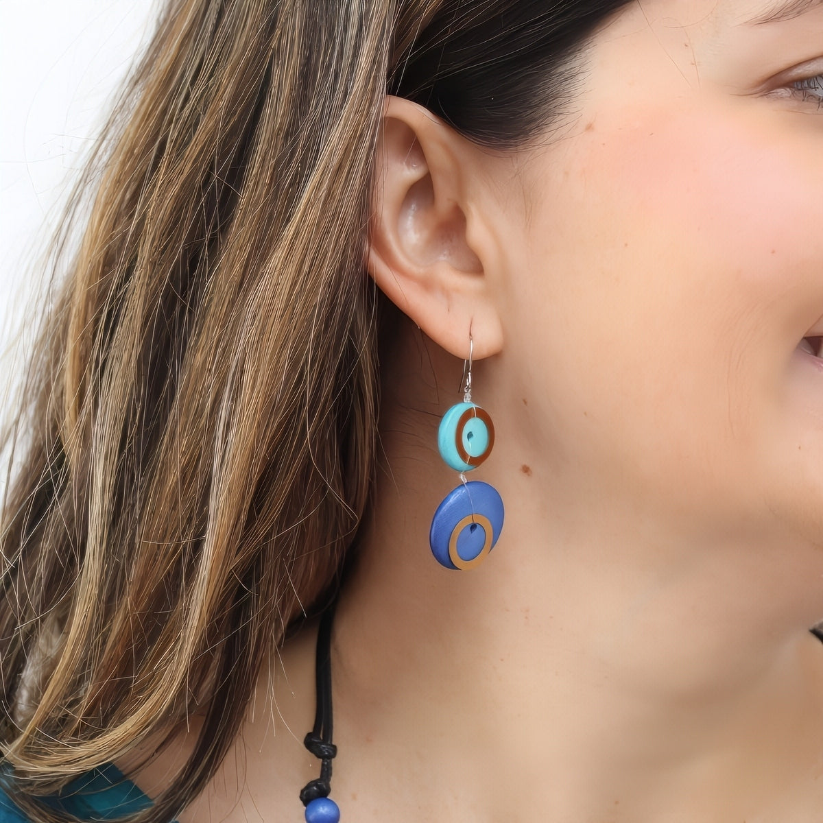 Close-up of a woman wearing colorful circular earrings with a blurred background
