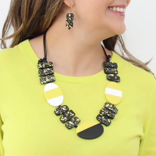 Woman wearing a yellow and black necklace with matching earrings on a white background