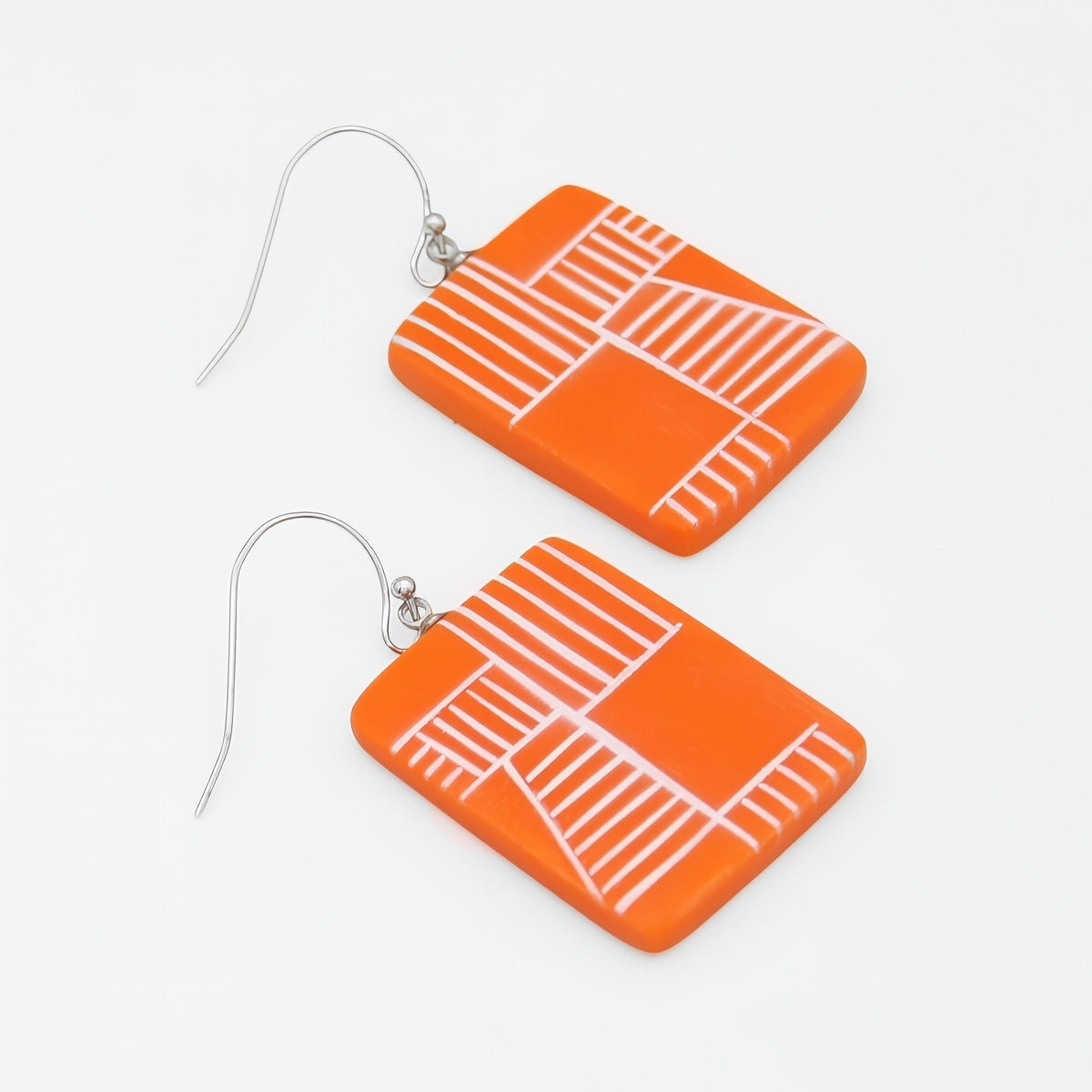 Orange earrings with white line patterns on a white background
