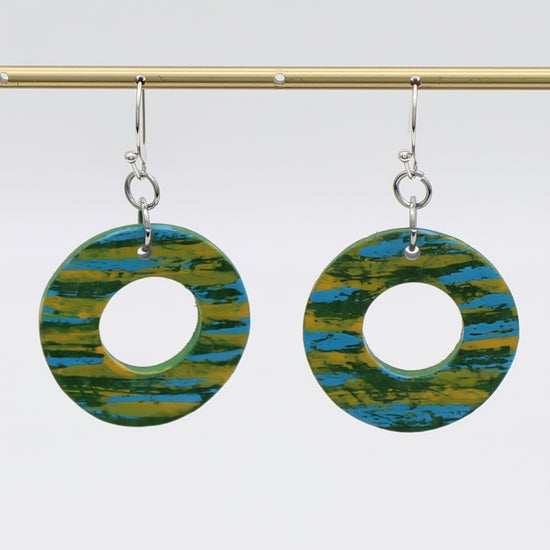 Pair of earrings with circular design in green and blue on a white background