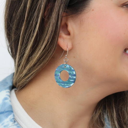 Close-up of a person wearing a blue circular earring with a white background