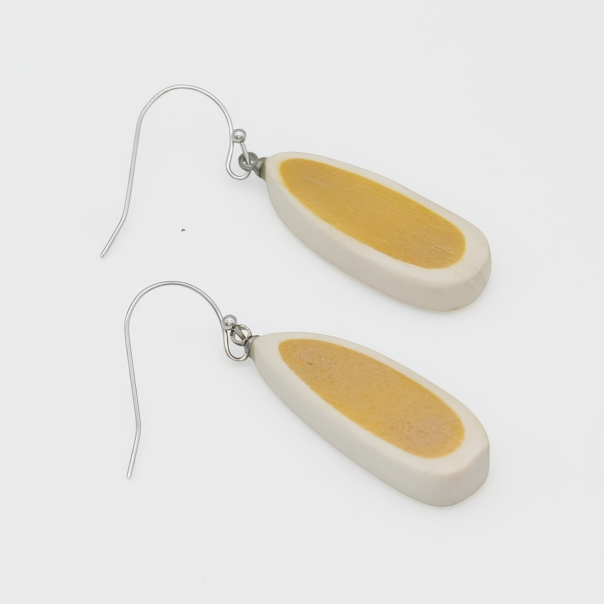 Pair of earrings with yellow and beige oval-shaped pendants on a white background