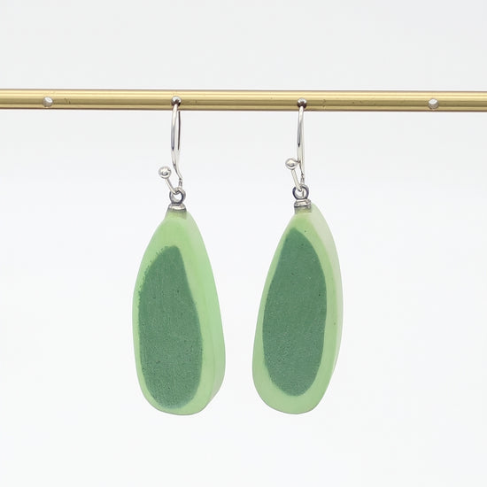 Pair of green teardrop earrings on a gold rod against a white background