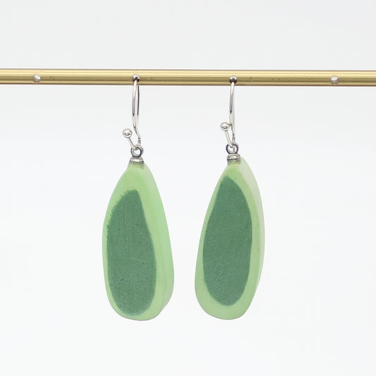 Pair of green teardrop earrings on a gold rod against a white background