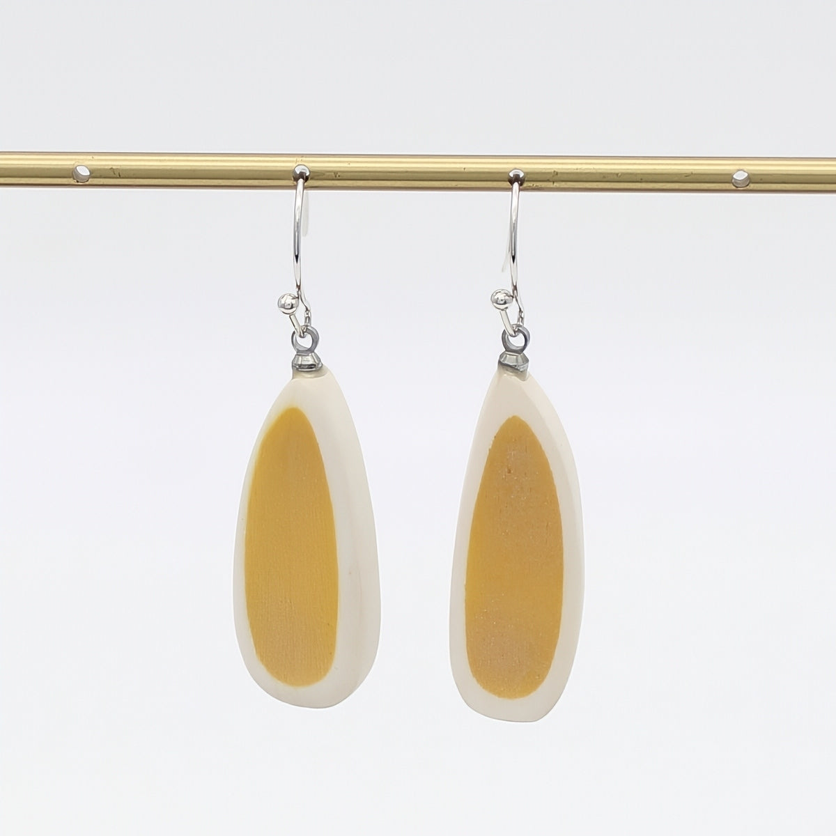 Pair of earrings with yellow and white teardrop design on a white background