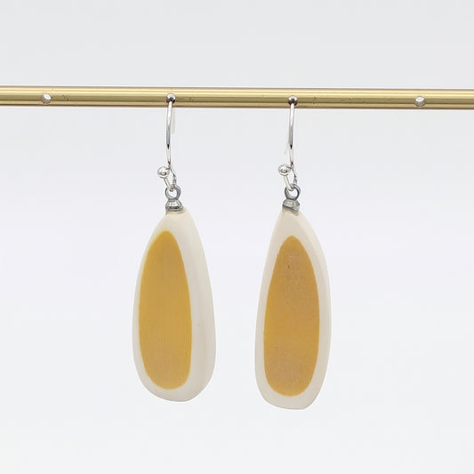 Pair of earrings with yellow and white teardrop design on a white background