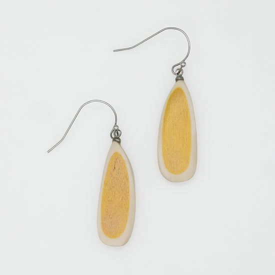 Pair of earrings with yellow and white teardrop-shaped stones on a light gray background