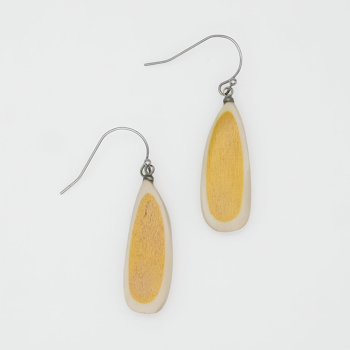 Pair of earrings with yellow and white teardrop-shaped stones on a light gray background