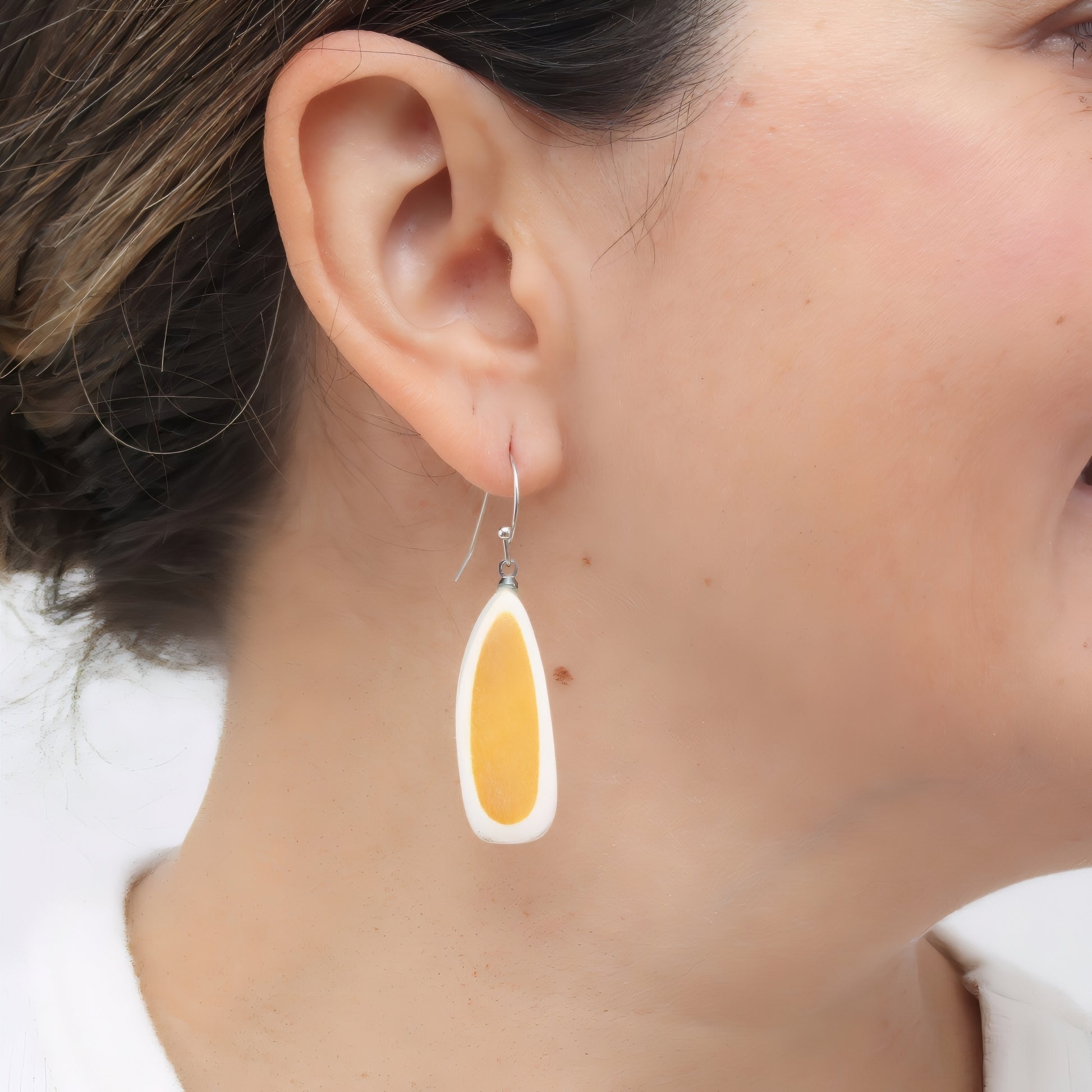 Close-up of a person wearing a yellow teardrop earring.