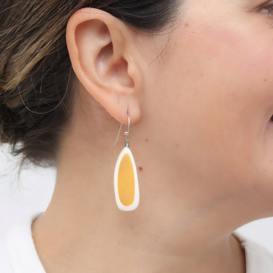 Close-up of a person wearing a yellow teardrop earring.