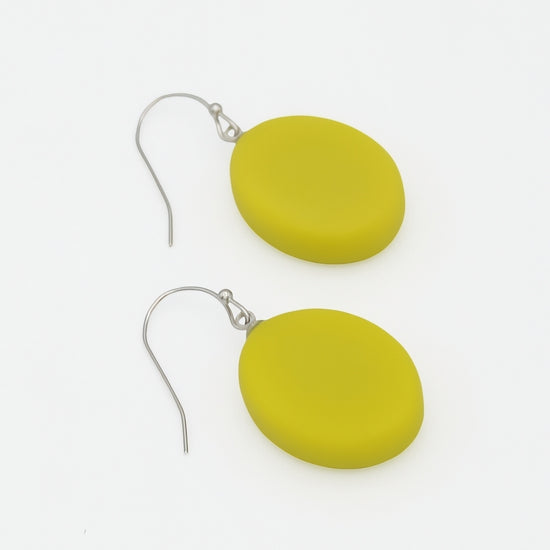 A pair of matte olive-yellow oval drop earrings with silver fishhook wires, displayed on a clean white background.