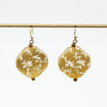 Pair of gold resin drop earrings hanging from display bar