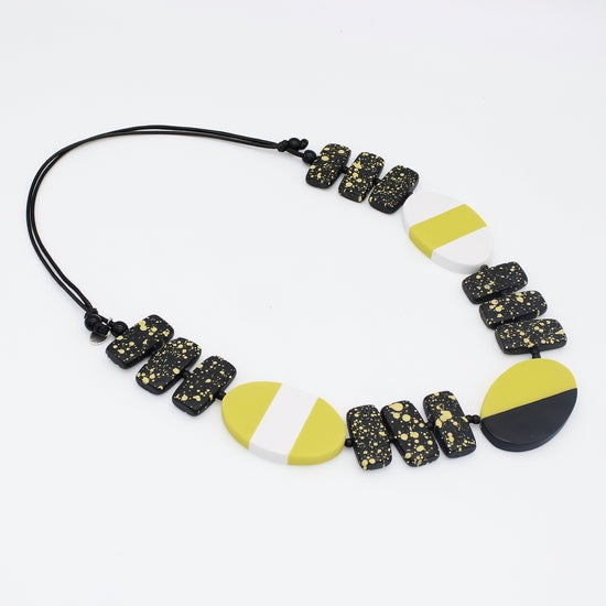 Necklace with black, lime, and white geometric beads on a white background
