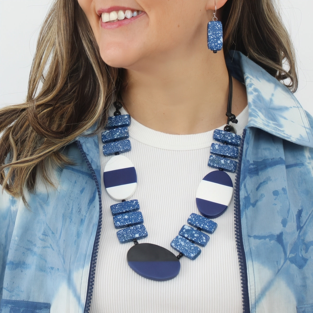 Woman wearing a blue and white necklace and earrings on a white background