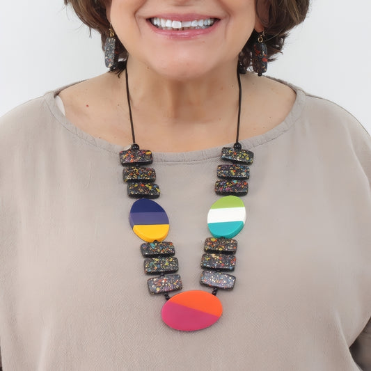 Woman wearing a colorful necklace with a plain background
