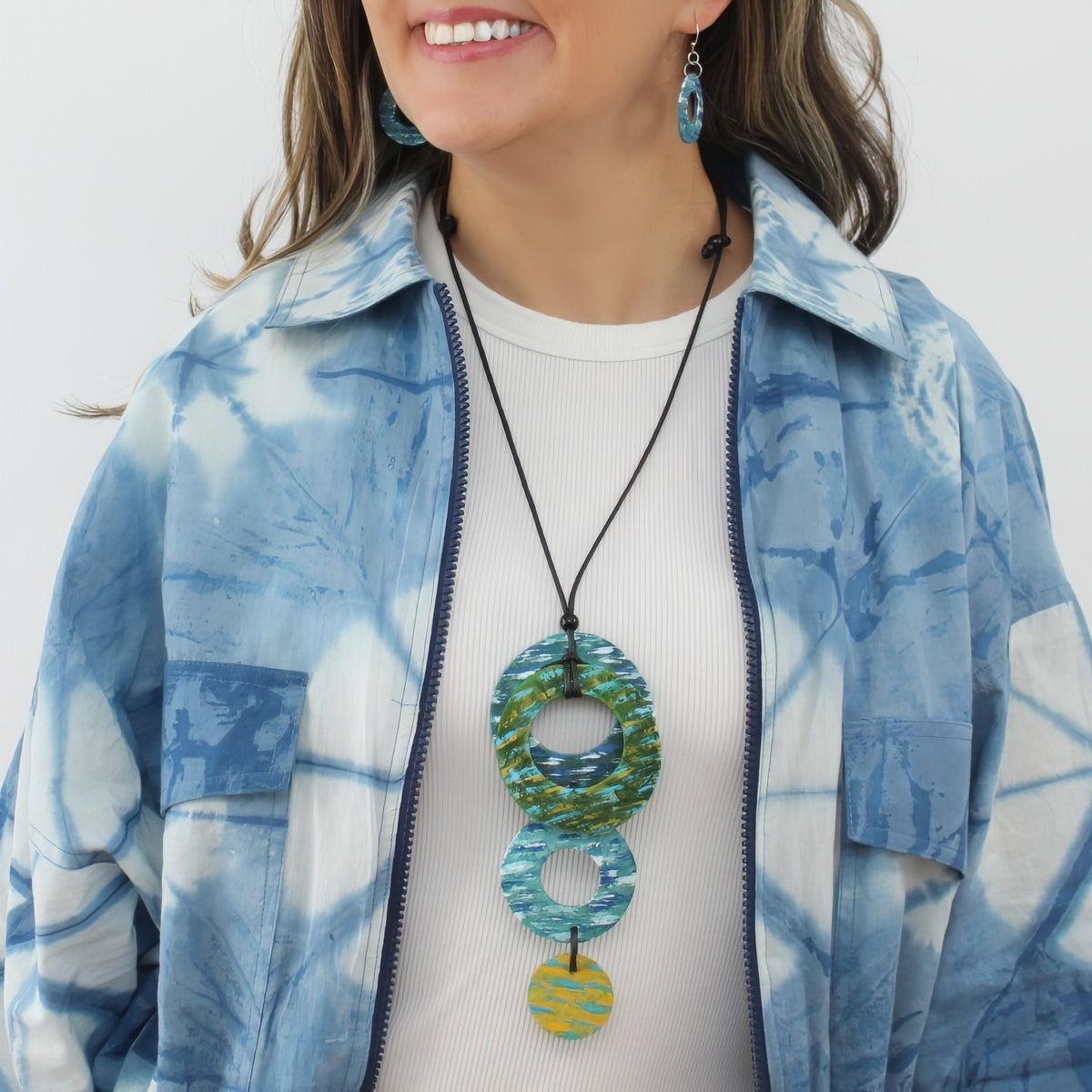 Woman wearing a blue and white patterned jacket with a colorful necklace.