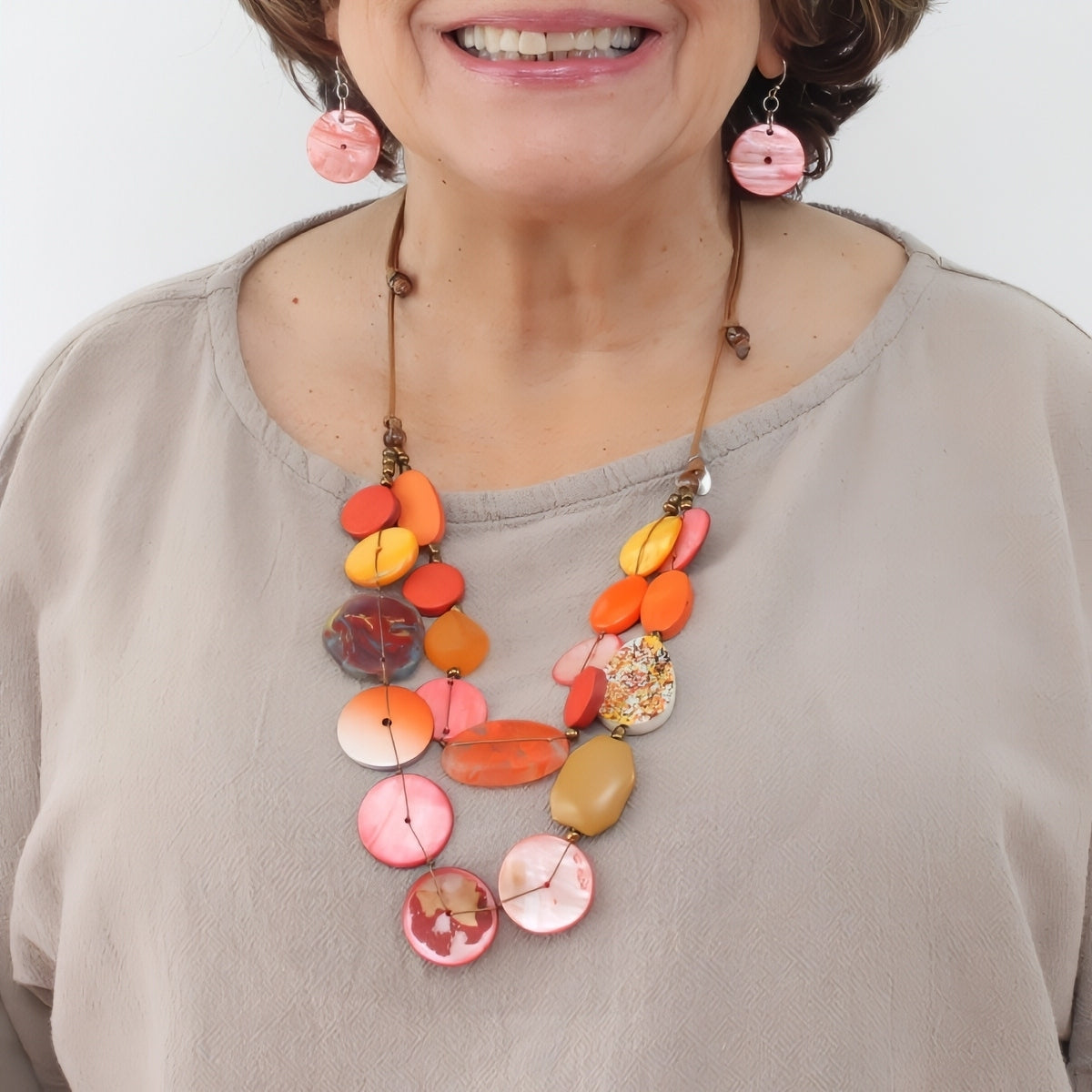 Woman wearing a colorful necklace with a plain background