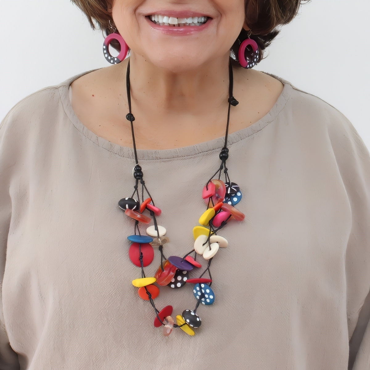 Woman wearing a colorful necklace with a plain background