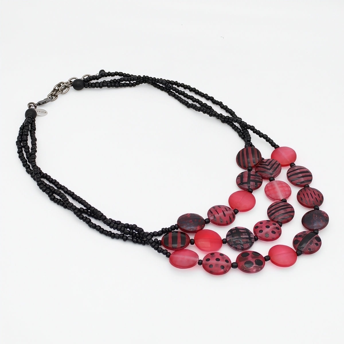 A multi-strand necklace featuring black beaded chains and a series of round, patterned beads in red, displayed on a clean white background.
