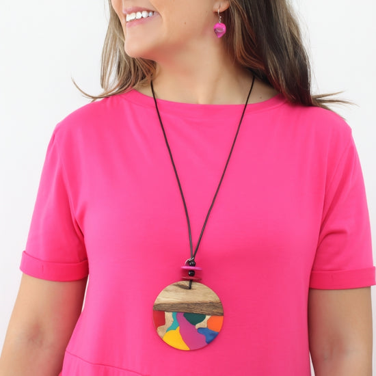 Woman wearing a colorful large necklace with a pink top on a white background
