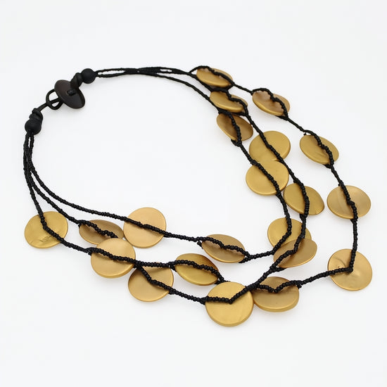 A multi-strand black cord necklace featuring flat, circular gold-toned disc pendants, displayed on a clean white background.
