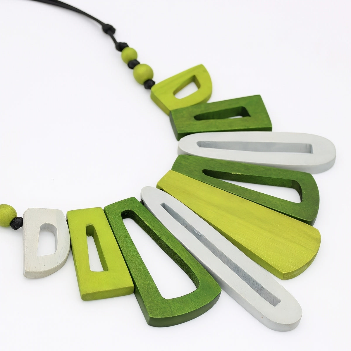Necklace with green and white wooden letters on a white background