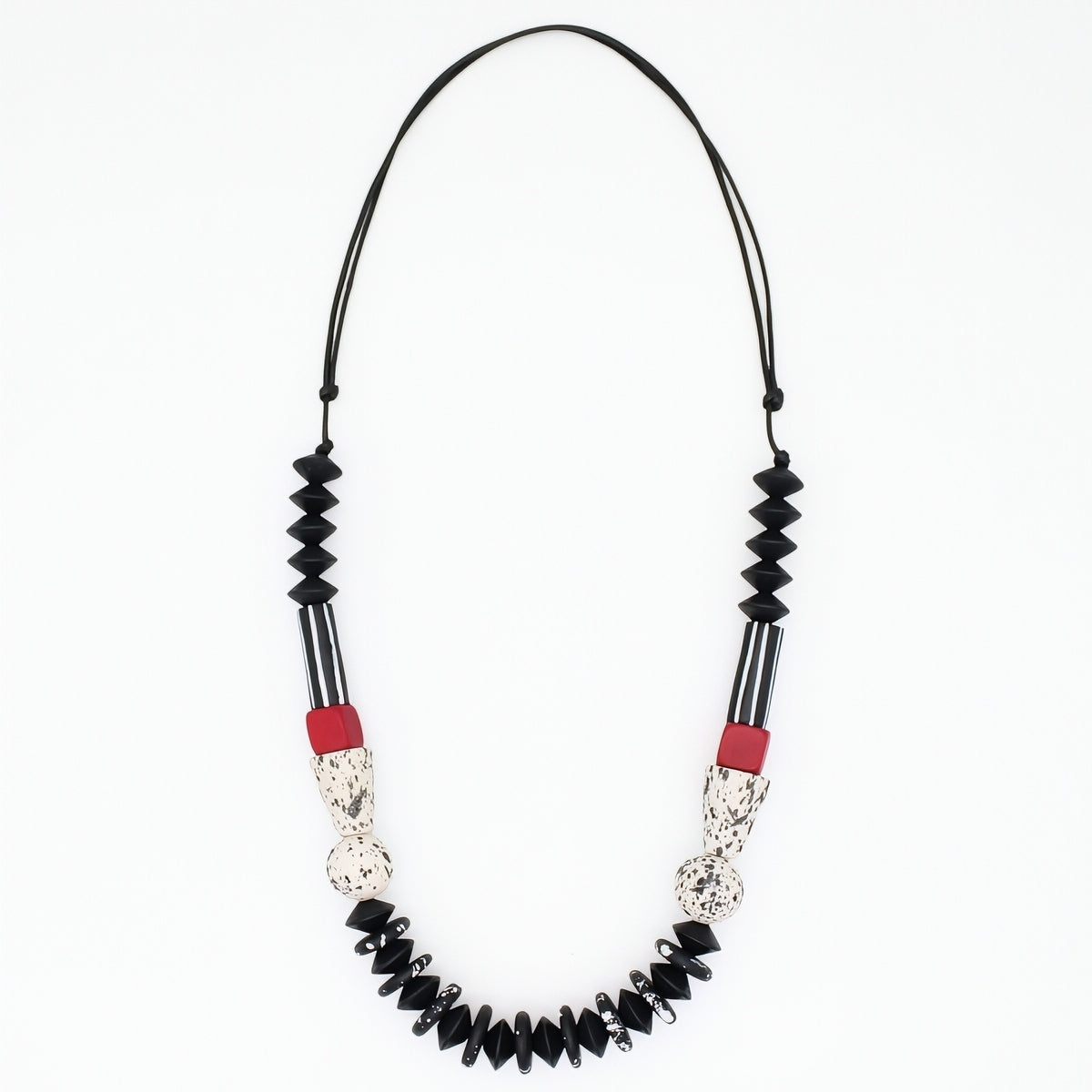 A beaded necklace featuring black faceted beads, black and white striped sections, textured silver-toned details, and small red accent beads, suspended on a black cord against a plain white background.