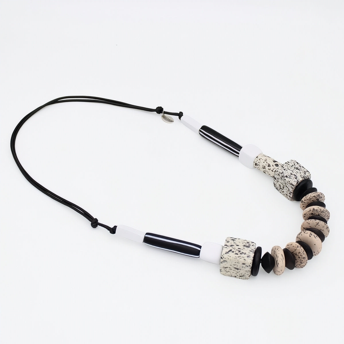 A beaded necklace featuring black and white glass tubes, textured lava stone beads, and smooth natural river stones on a black cord, displayed on a clean white background.